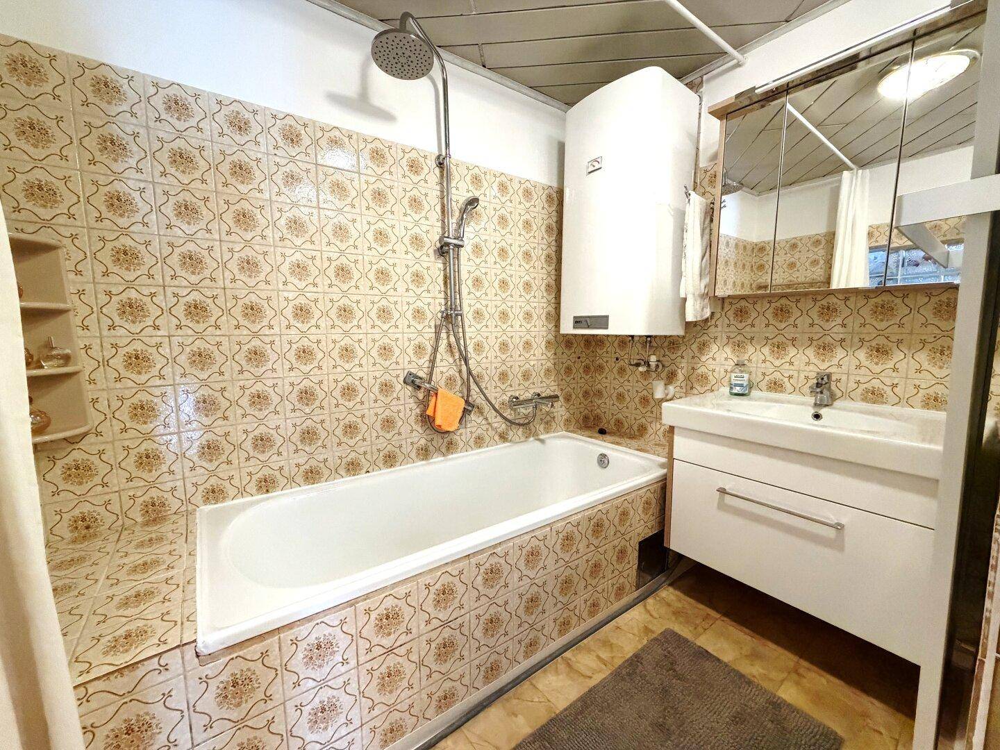 Badezimmer mit Badewanne, Dusche, Waschbecken und Spiegelschrank.