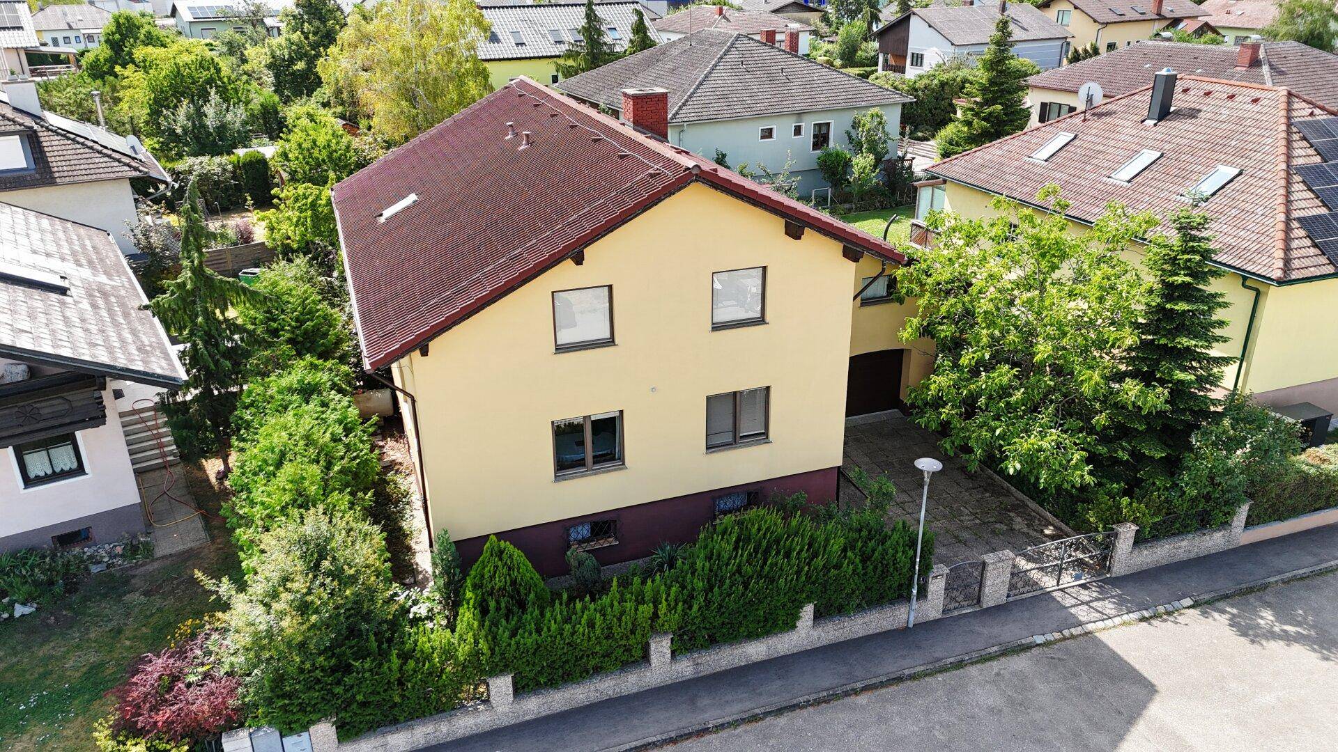 Vogelperspektive des Hauses mit gelber Fassade, rotem Ziegeldach und gepflegtem Vorgarten.