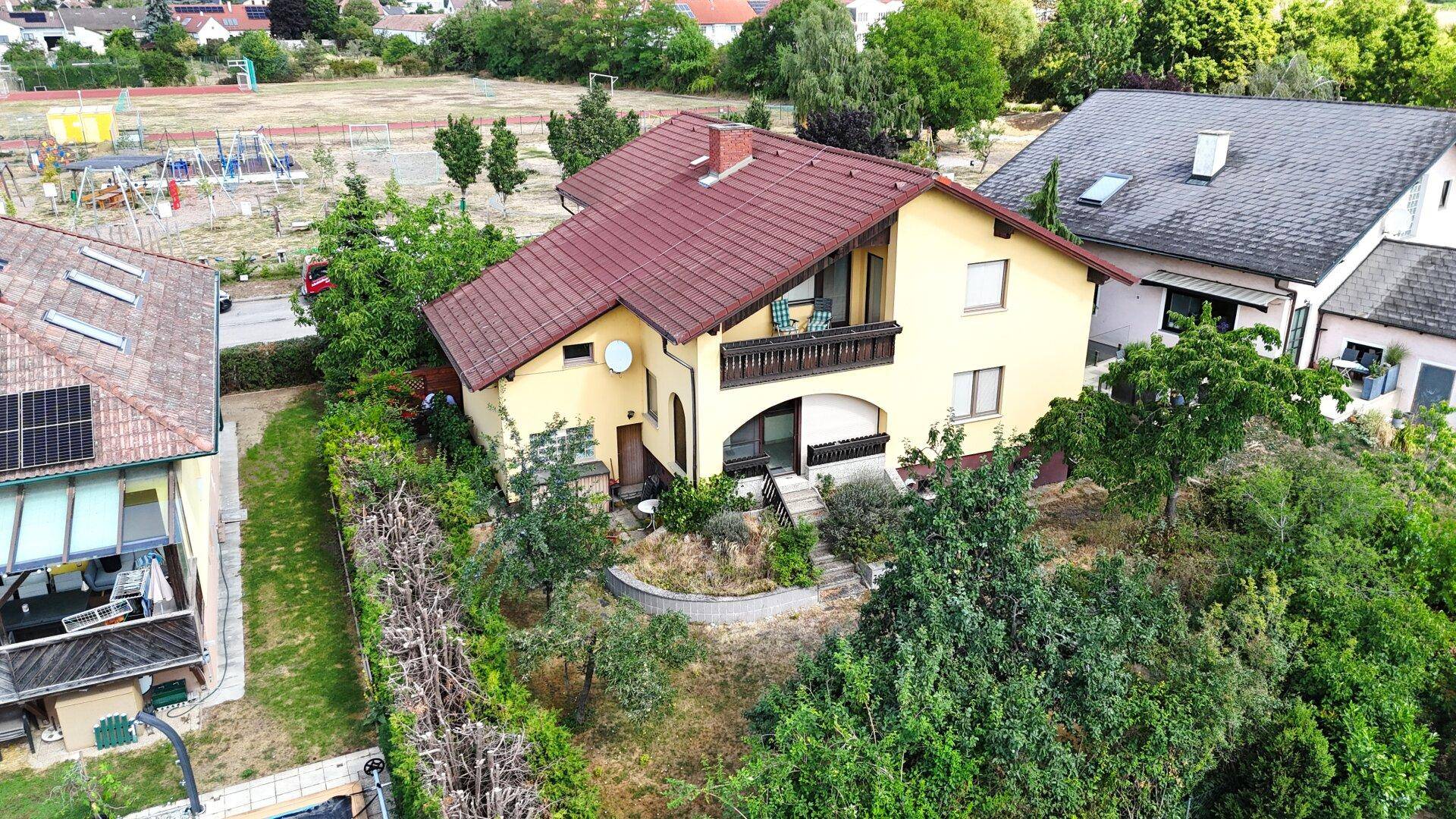 Luftaufnahme des Einfamilienhauses mit Balkon und großem Garten in ländlicher Umgebung.