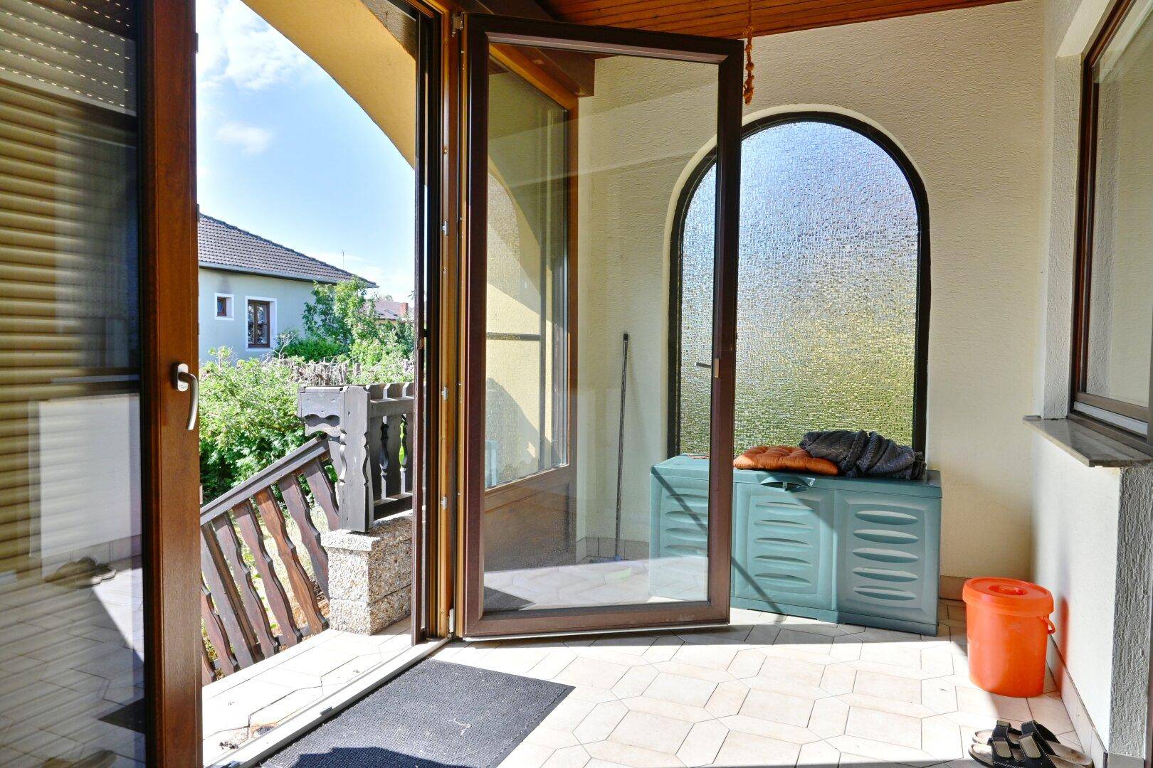 Überdachter Balkon mit Fliesenboden und Blick ins Grüne, ideal für entspannte Stunden.