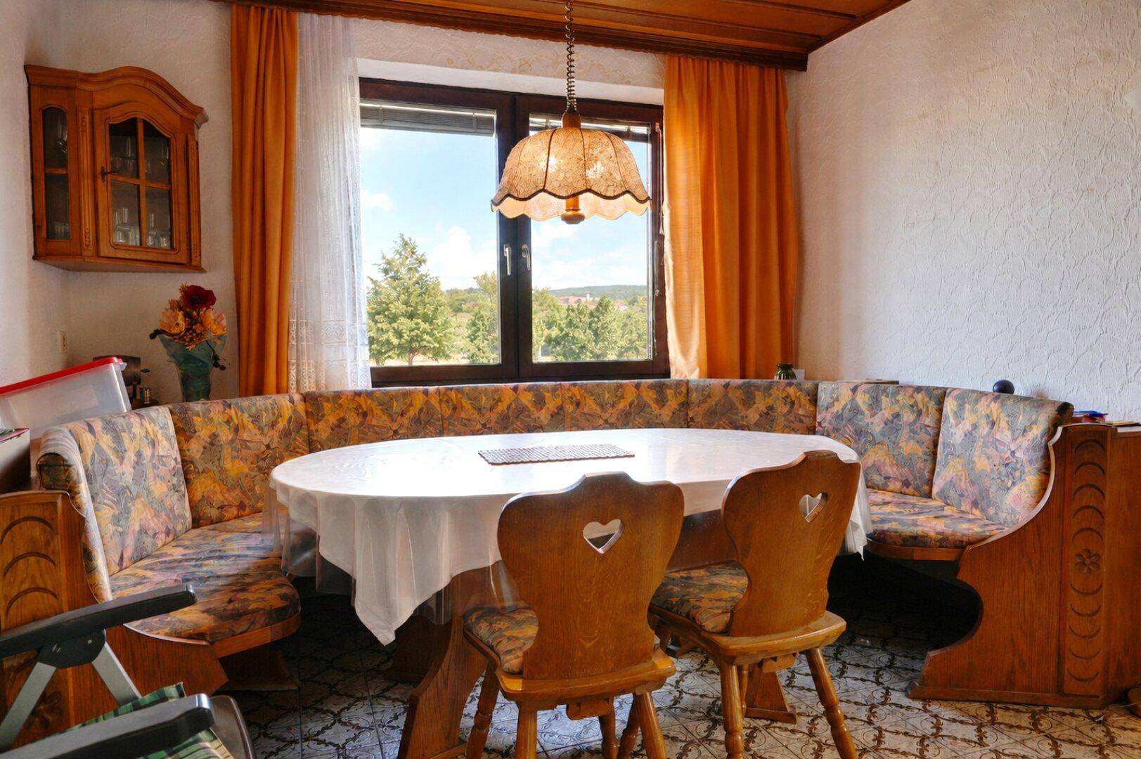 Esszimmer mit traditioneller Eckbank, Holztisch und großem Fenster mit Weitblick.