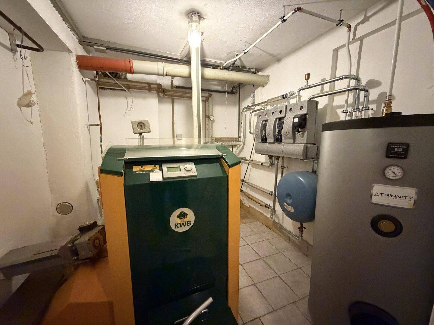 Heizungsraum im Keller mit großem grünen Heizkessel und komplexen Rohrleitungen.