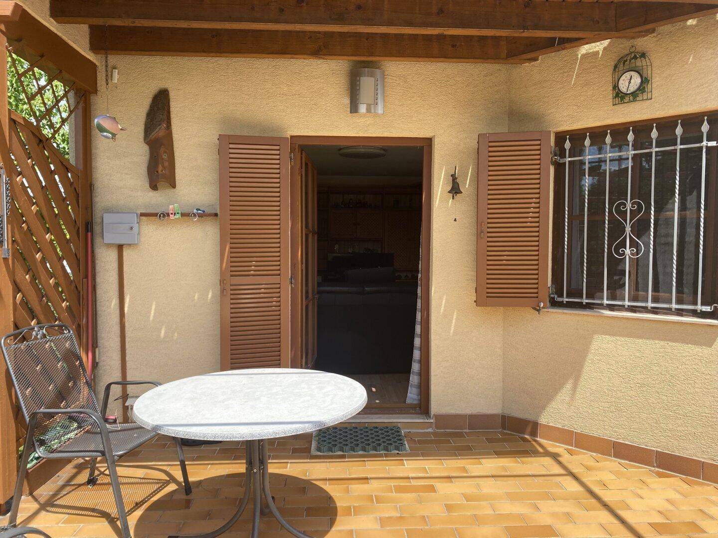 Gepflasterte Terrasse mit Gartenmöbeln und Zugang zum Haus.
