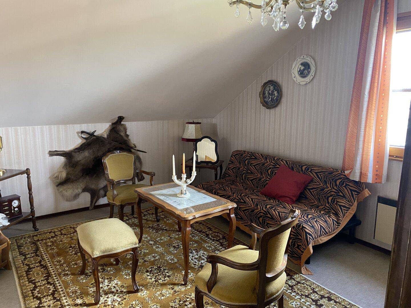 Gemütliches Wohnzimmer im Dachgeschoss mit schrägen Decken und klassischer Einrichtung.