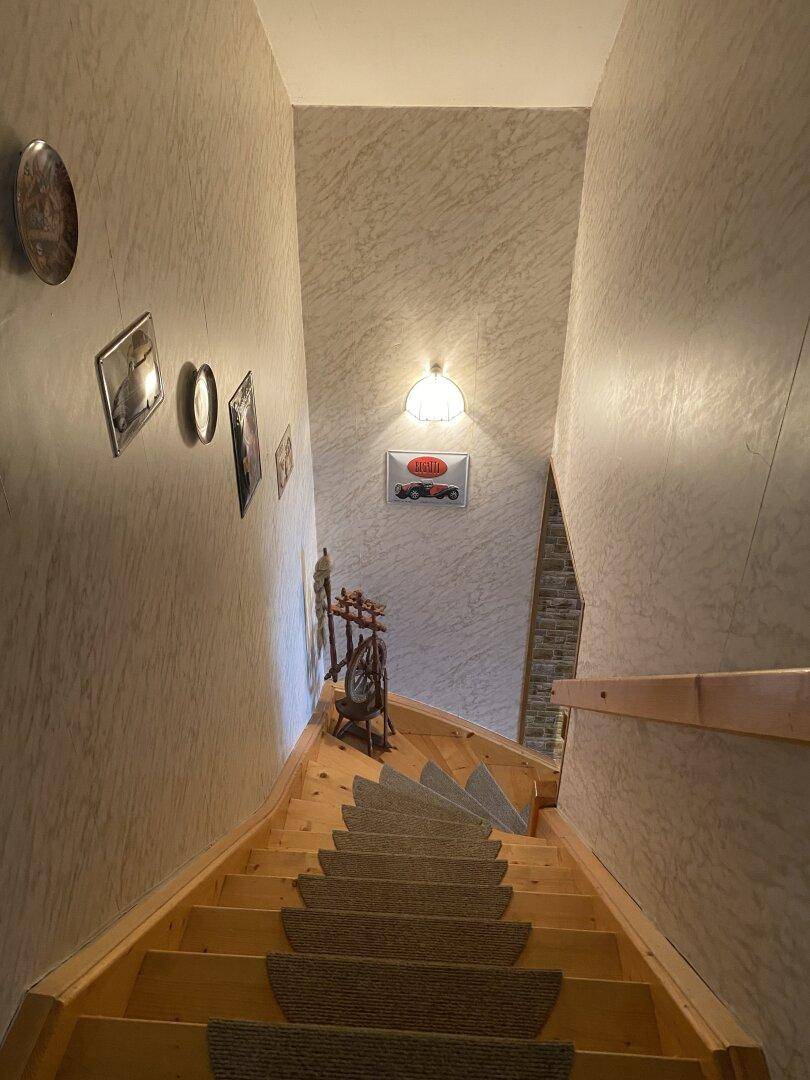 Holztreppe mit Teppichläufern führt in das obere Stockwerk des Hauses.