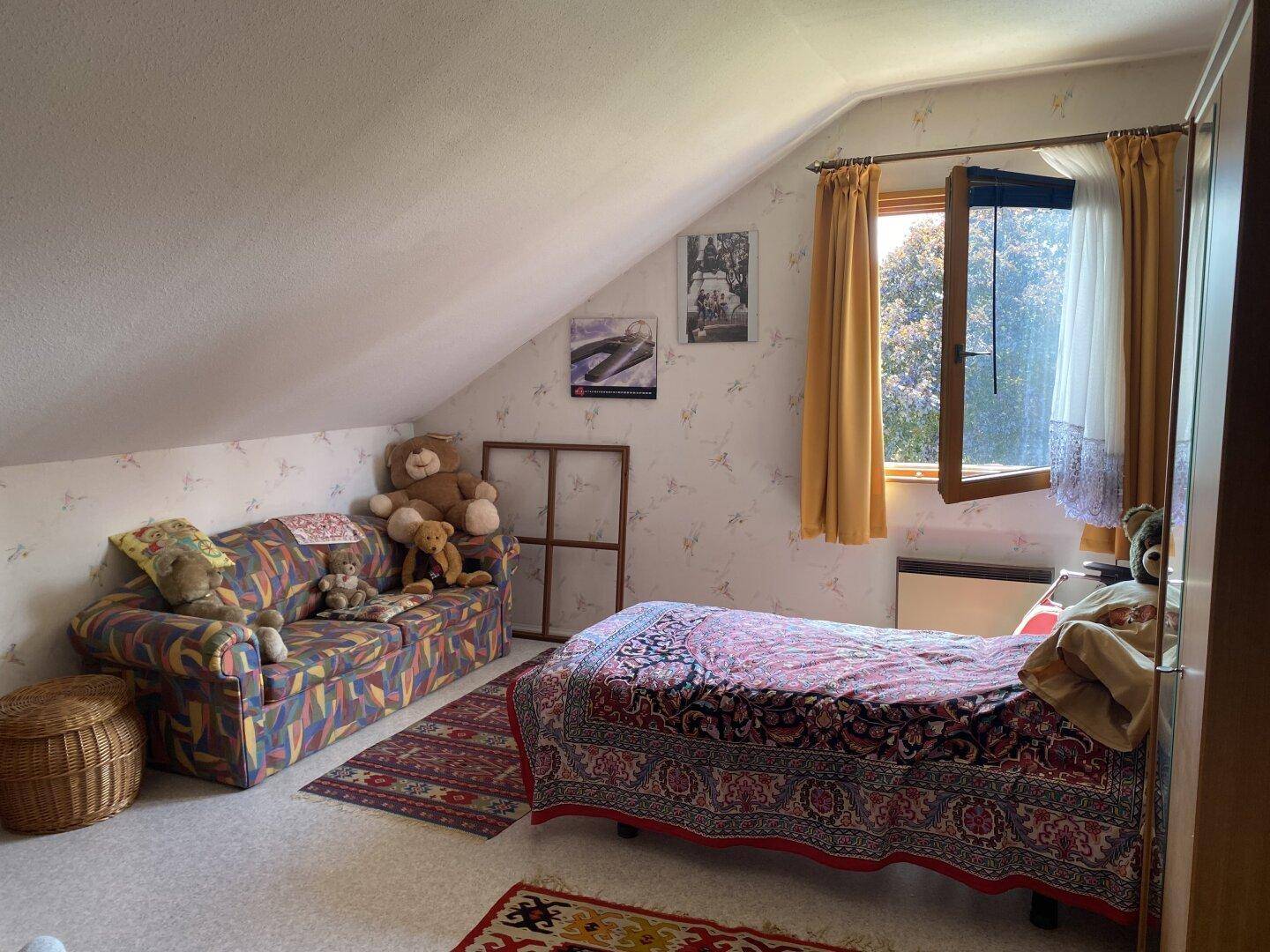 Kinderzimmer im Dachgeschoss mit Bett, Sofa und verspielter Dekoration.