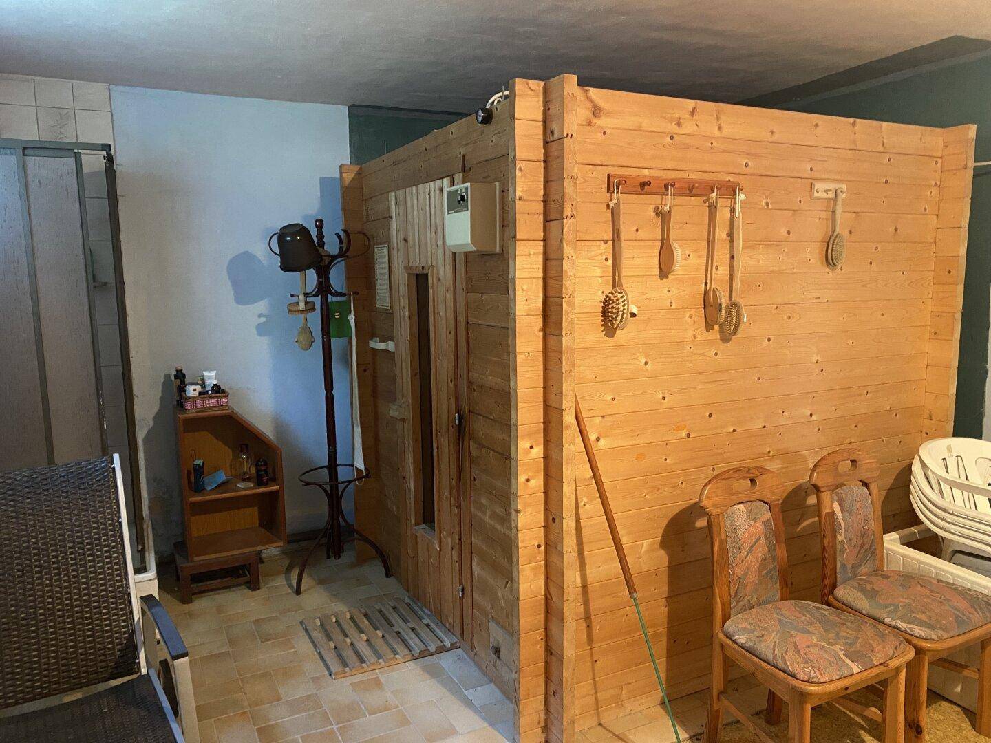 Holzsauna in einem Raum mit Stühlen und Garderobe, bereit zur Nutzung.