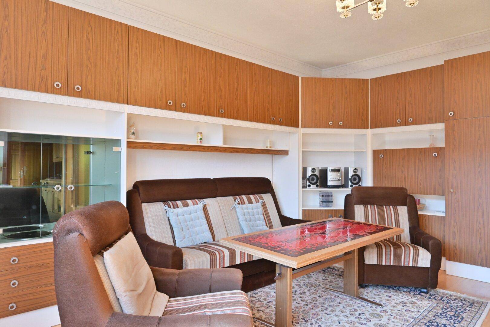 Wohnzimmer mit braunen Sofas, Teppich und umfangreichen Wandschränken.