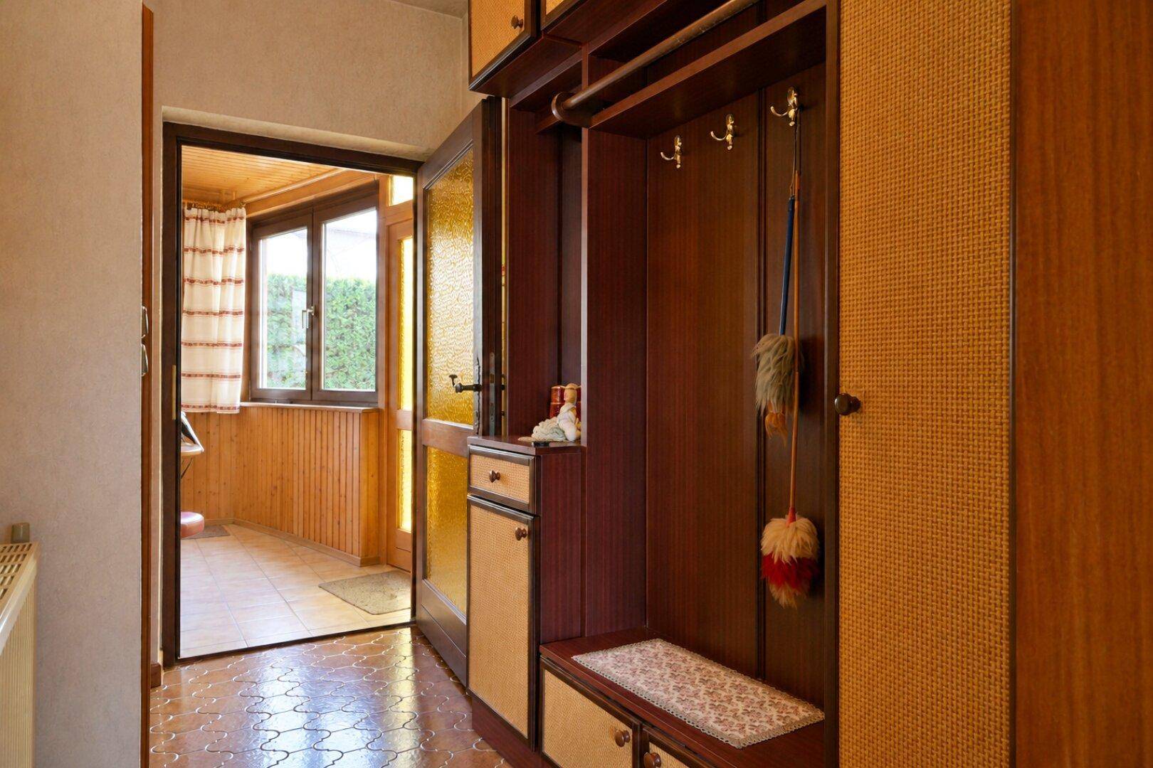 Eingangsbereich mit Holzvertäfelung, Garderobe und Blick in den Wintergarten.