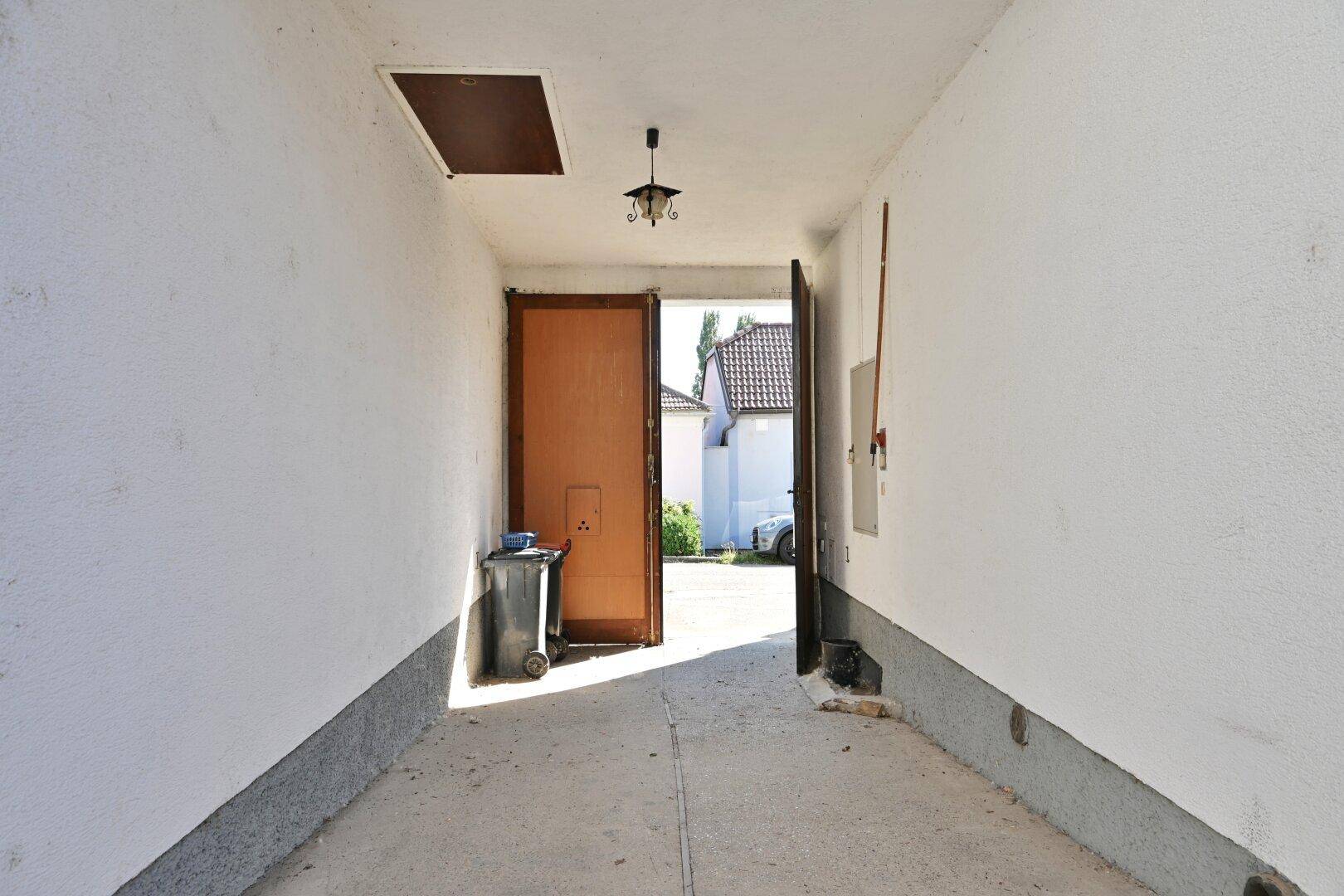 Überdachte Einfahrt oder Carport mit Zugang zum hinteren Bereich des Grundstücks.
