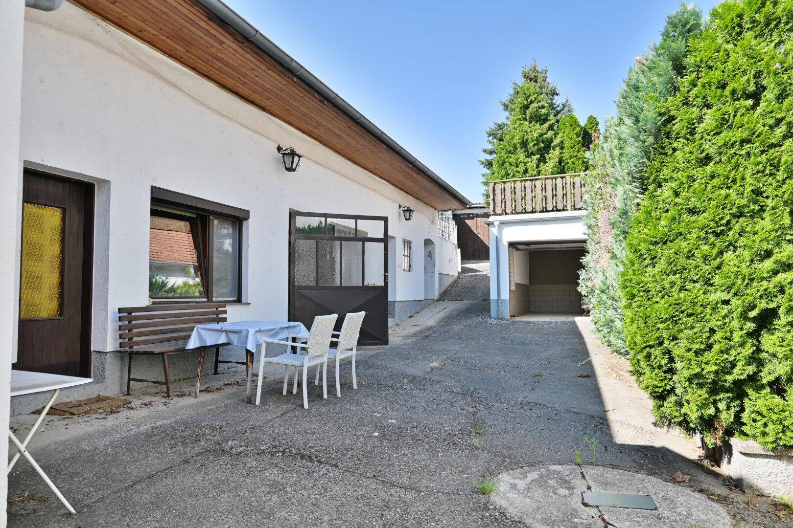 Hinterhof mit Sitzgelegenheiten, Garage und viel Grün.