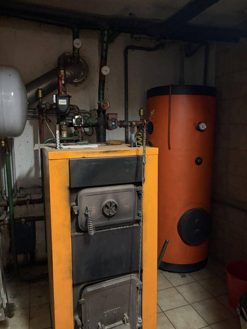 Heizungsraum mit großem Warmwasserspeicher und Heizkessel.