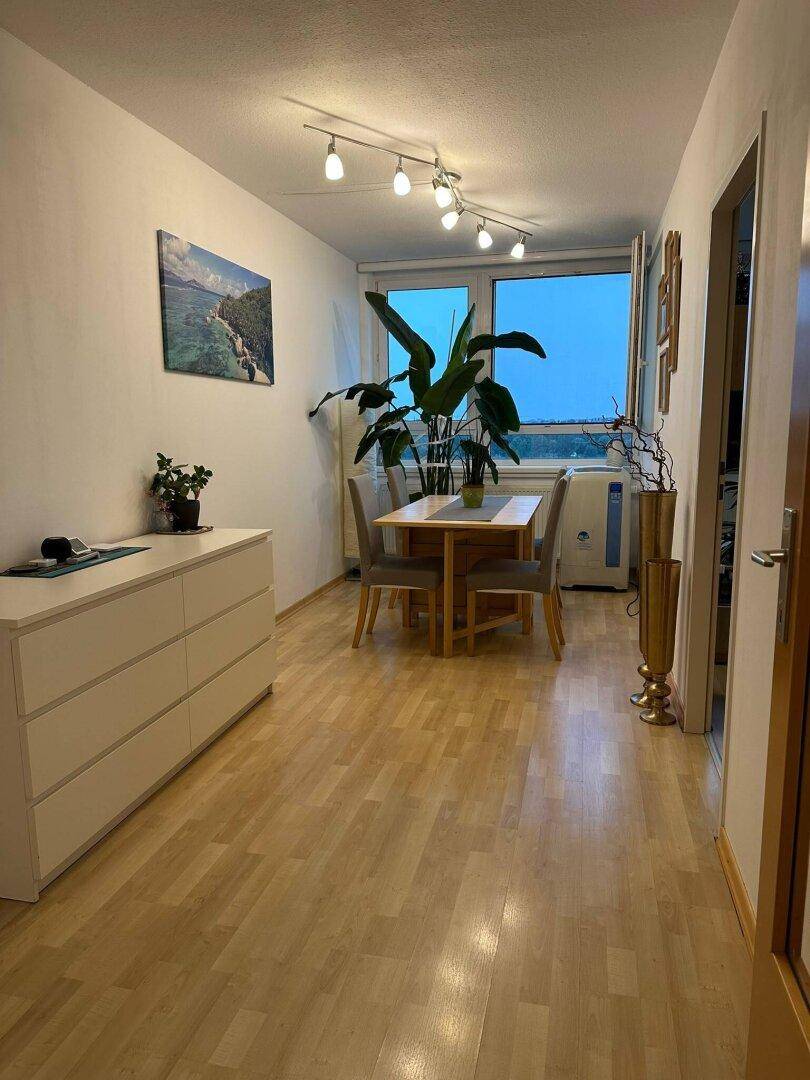 Heller Essbereich mit Holztisch, Stühlen und einem großen Fenster, das viel Licht hereinlässt.