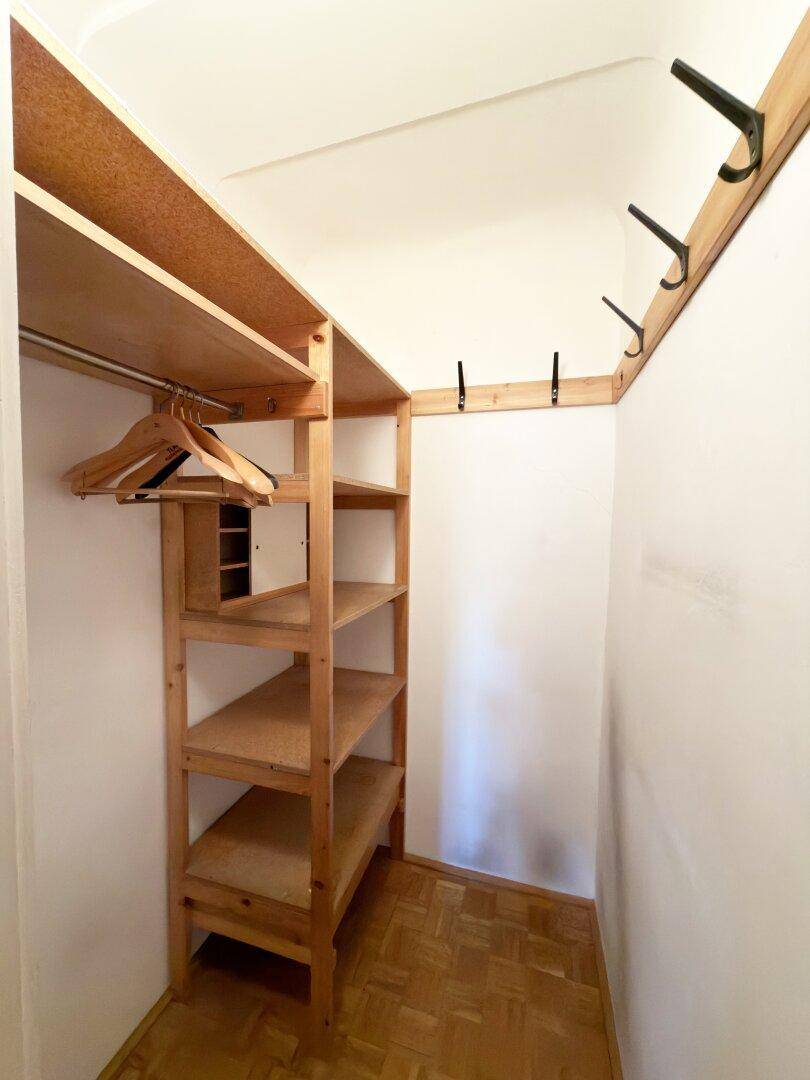 Praktischer begehbarer Schrank mit Holzregalen und Parkettboden für Stauraum.