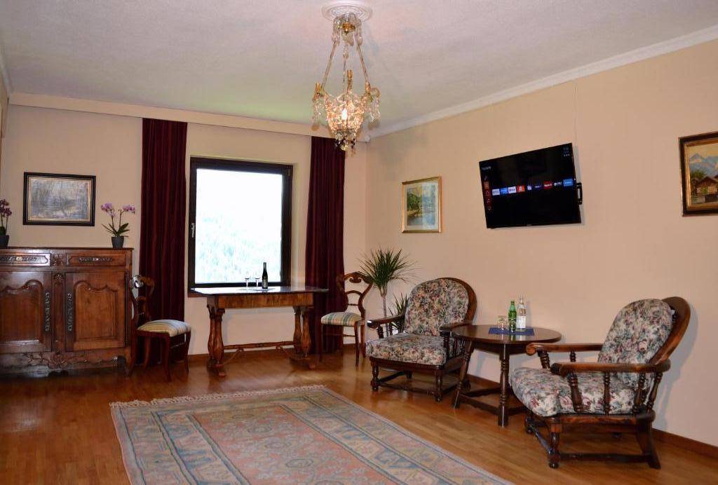 Gemütliches Wohnzimmer mit Holzboden, klassischen Möbeln und einem Fernseher an der Wand.