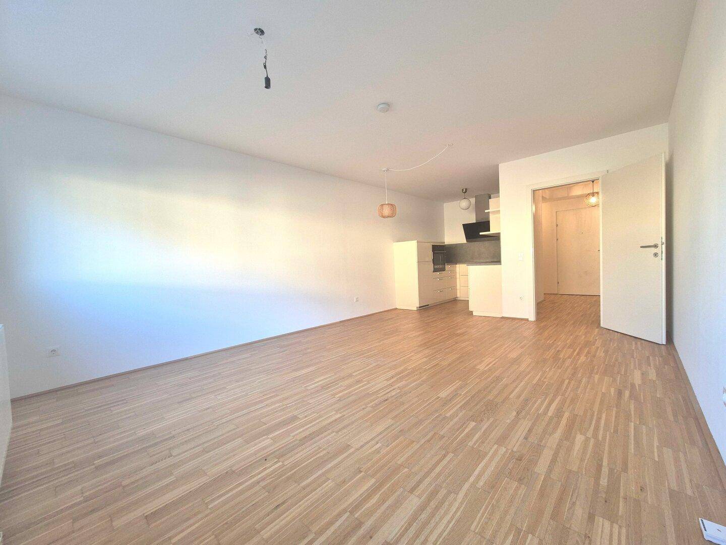 Geräumiger, offener Wohnbereich mit Holzboden und viel Tageslicht.