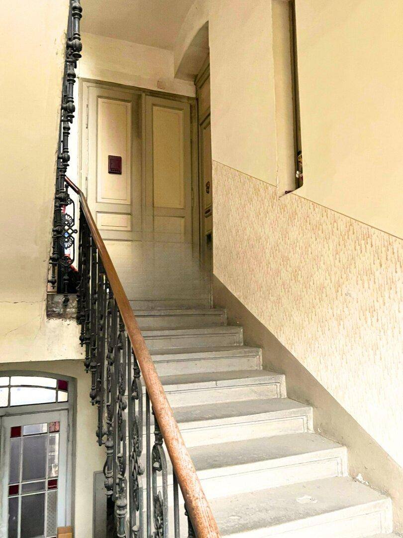 Historisches Treppenhaus mit schmiedeeisernem Geländer und Holztüren in einem Altbau.