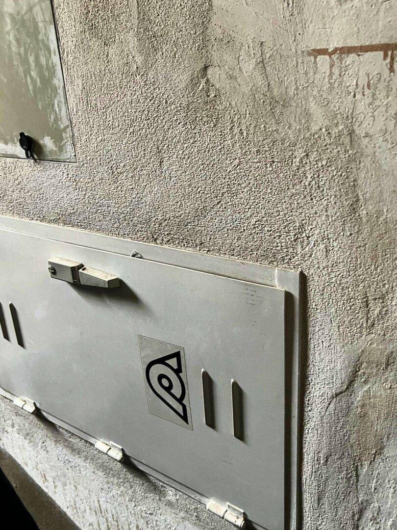 Detailansicht eines alten Sicherungskastens an einer rauen Wand in einem renovierungsbedürftigen Zustand.