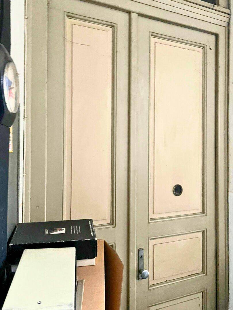Eine alte, zweiflügelige Holztür mit Kassetten und einem Türknauf in einem historischen Gebäude.