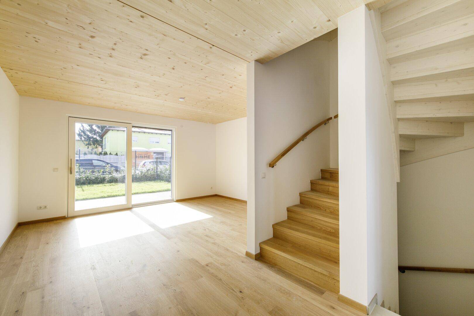 Heller Wohnbereich mit Holzboden, Holzdecke und Zugang zum Garten.