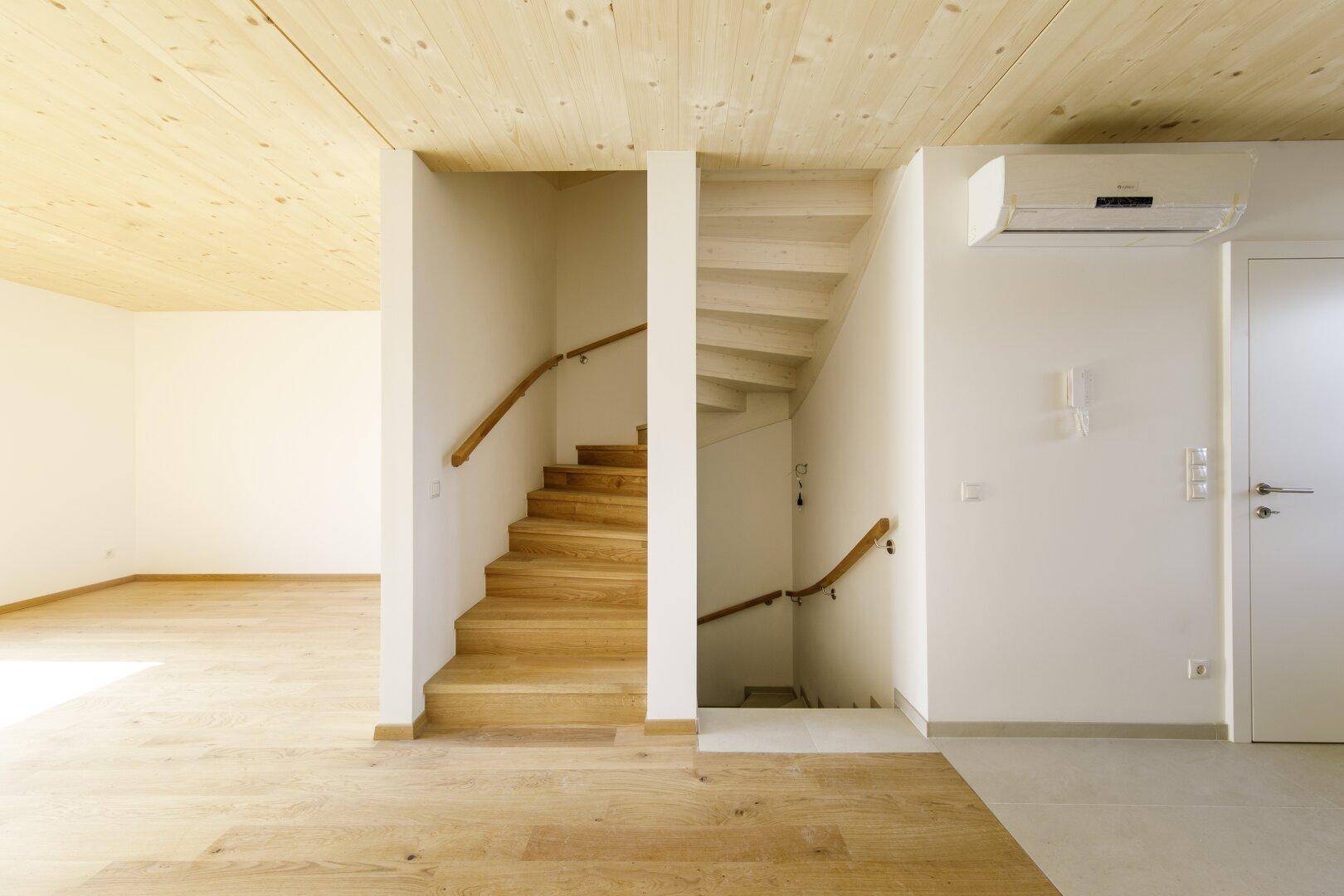 Heller Eingangsbereich mit Holztreppe und Holzboden, offen zum Wohnbereich.