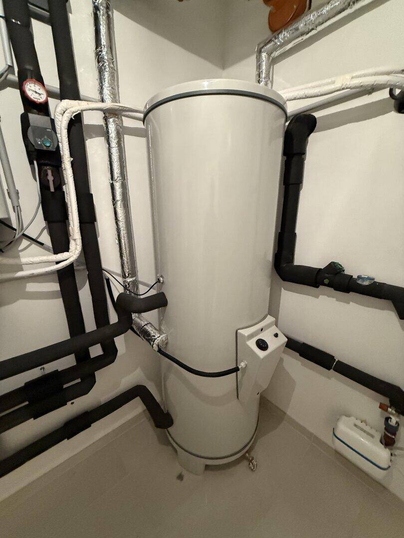 Warmwasserspeicher und Rohrleitungen im Technikraum des Kellers.