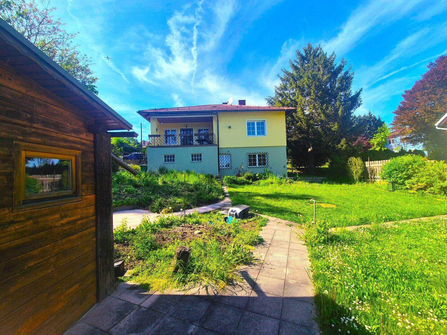 Ansicht des Hauses von hinten mit einem großen Garten und einem kleinen Gartenhaus.
