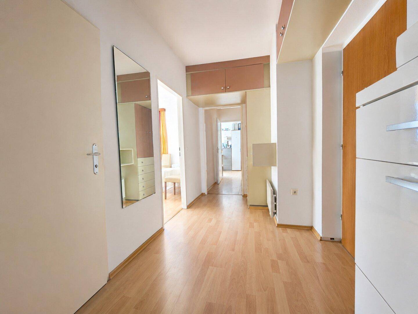 Heller Flur mit Laminatboden, Spiegel und praktischen Einbauschränken.