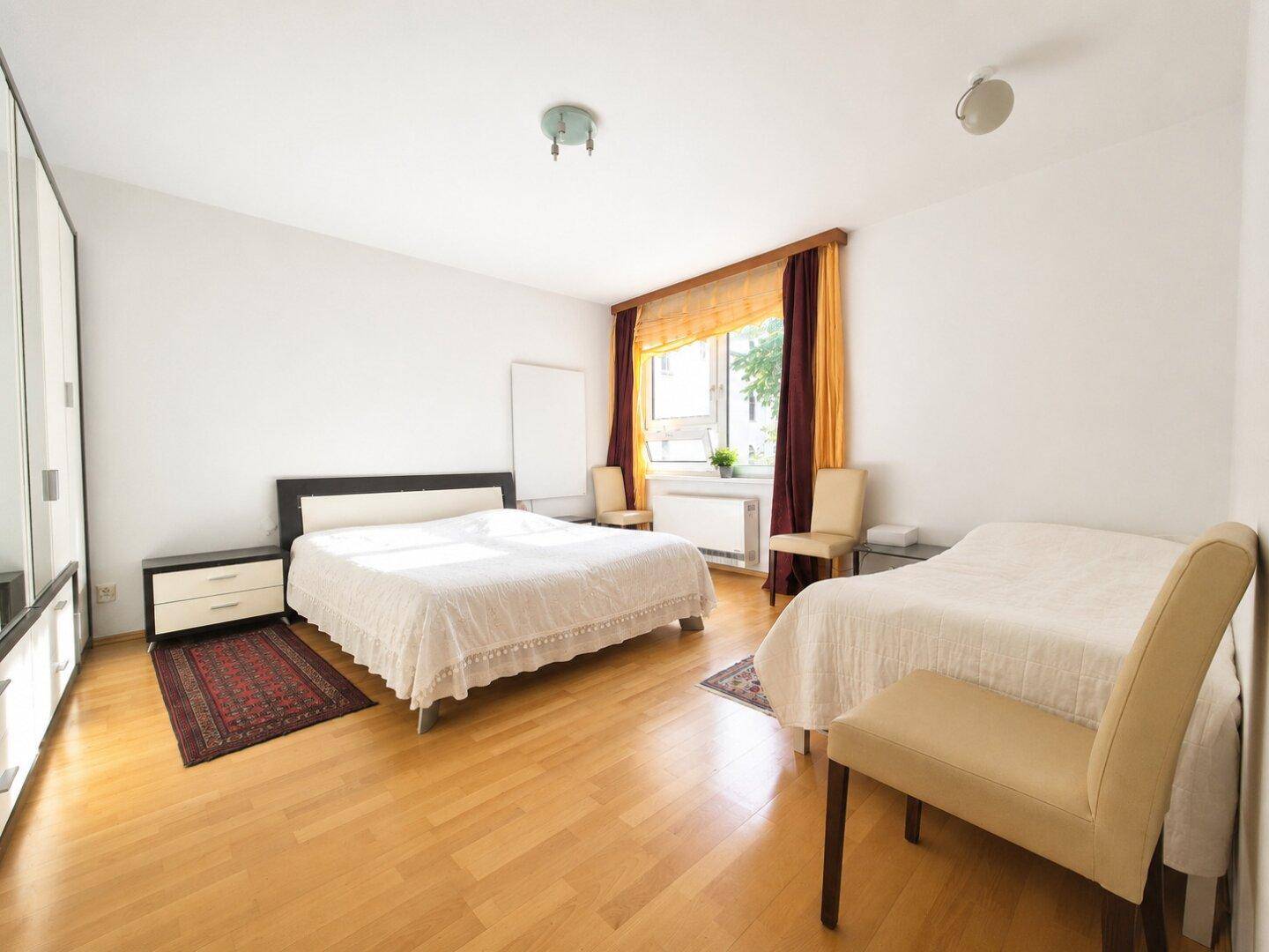 Geräumiges Schlafzimmer mit zwei Betten, Laminatboden und einem großen Kleiderschrank.
