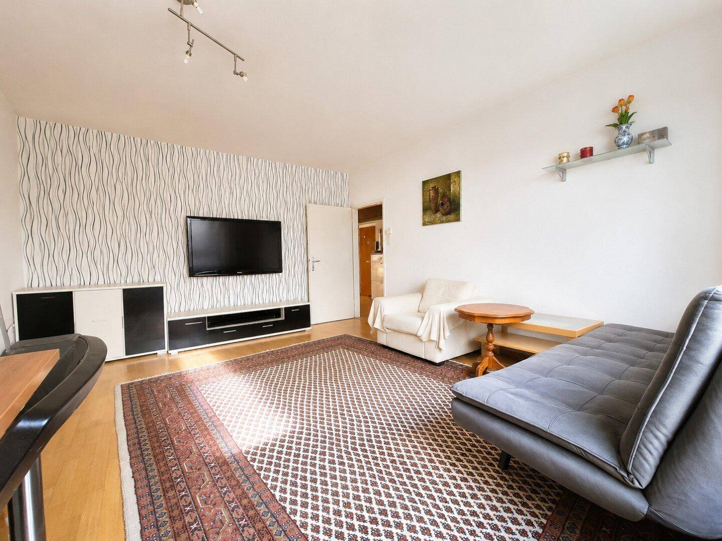 Gemütliches Wohnzimmer mit Sofa, Teppich und einem modernen TV-Möbel an der Wand.