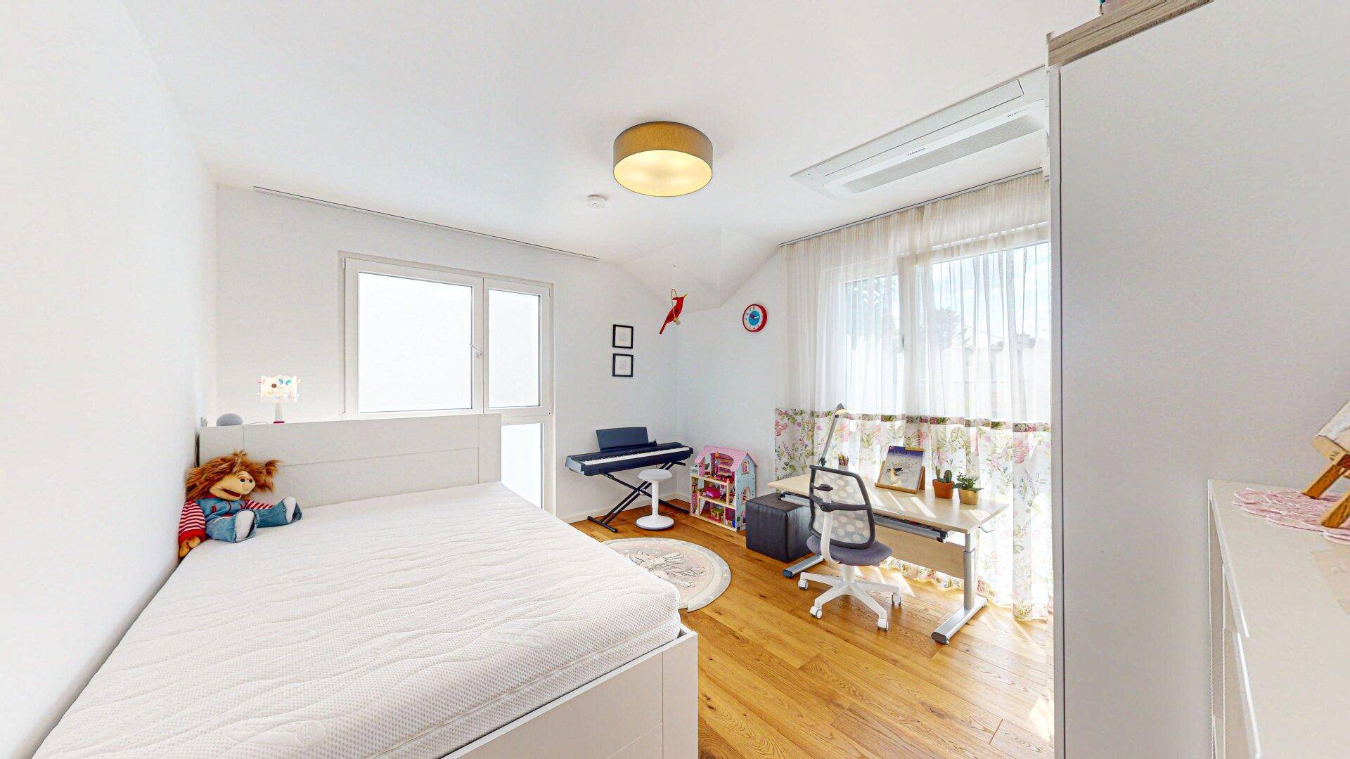Helles Kinderzimmer mit Holzboden, Einzelbett, Schreibtisch und Fenster zum grünen Garten.