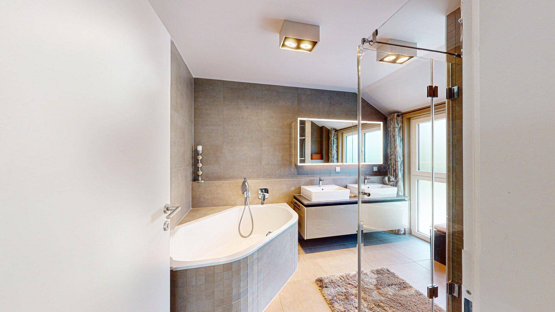 Modernes Badezimmer mit Badewanne, Doppelwaschbecken und großer Duschkabine mit Glaswand.