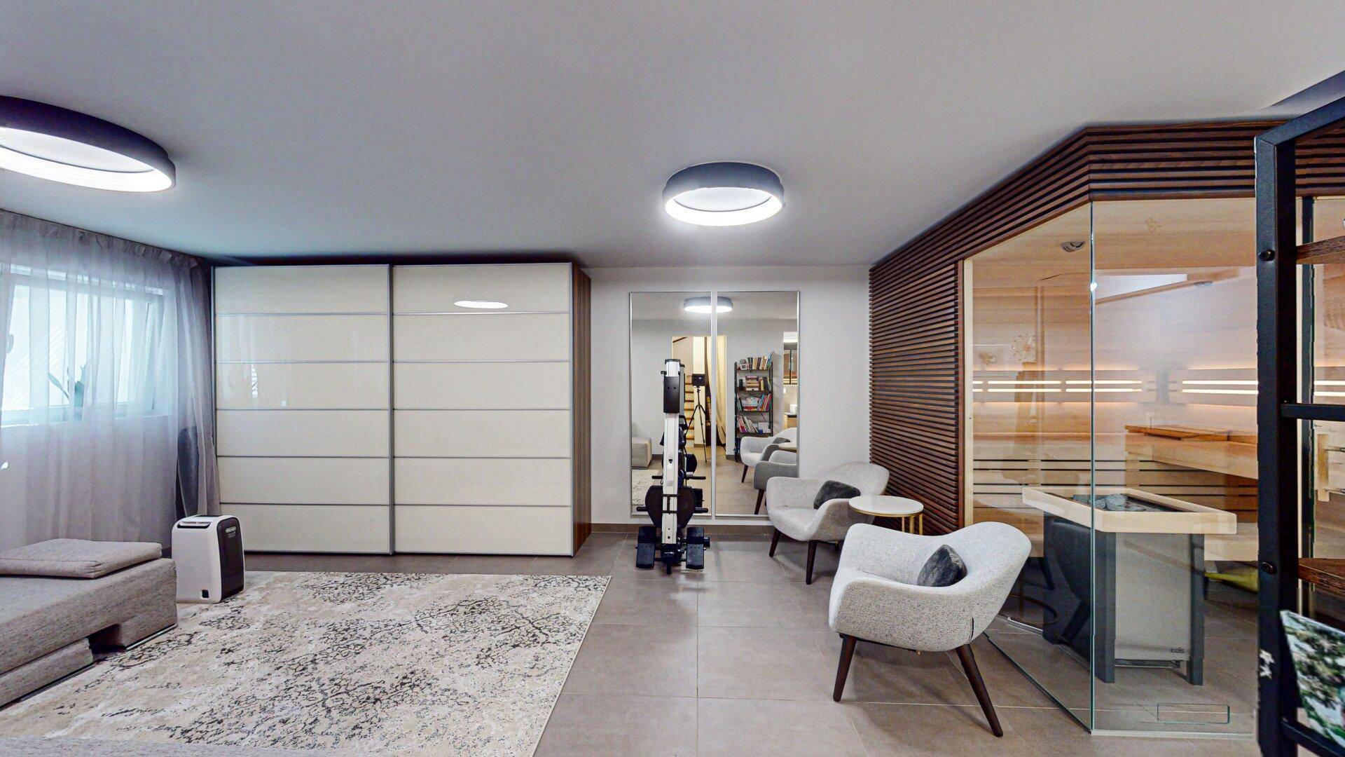 Geräumiger Wellnessbereich mit Sauna, bequemen Sesseln und großem Spiegelschrank für Entspannung.