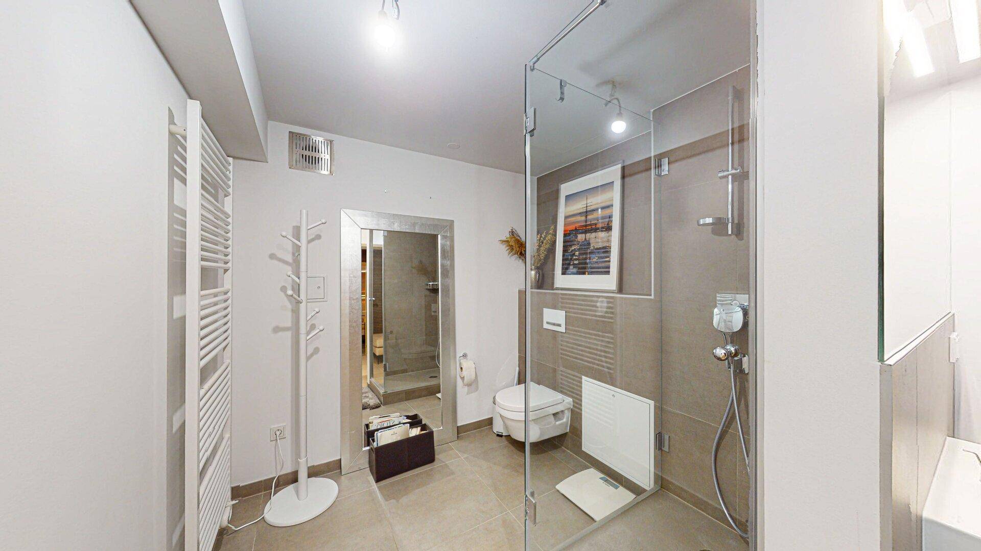 Modernes Badezimmer mit ebenerdiger Dusche, Wand-WC und beheiztem Handtuchhalter für Komfort.