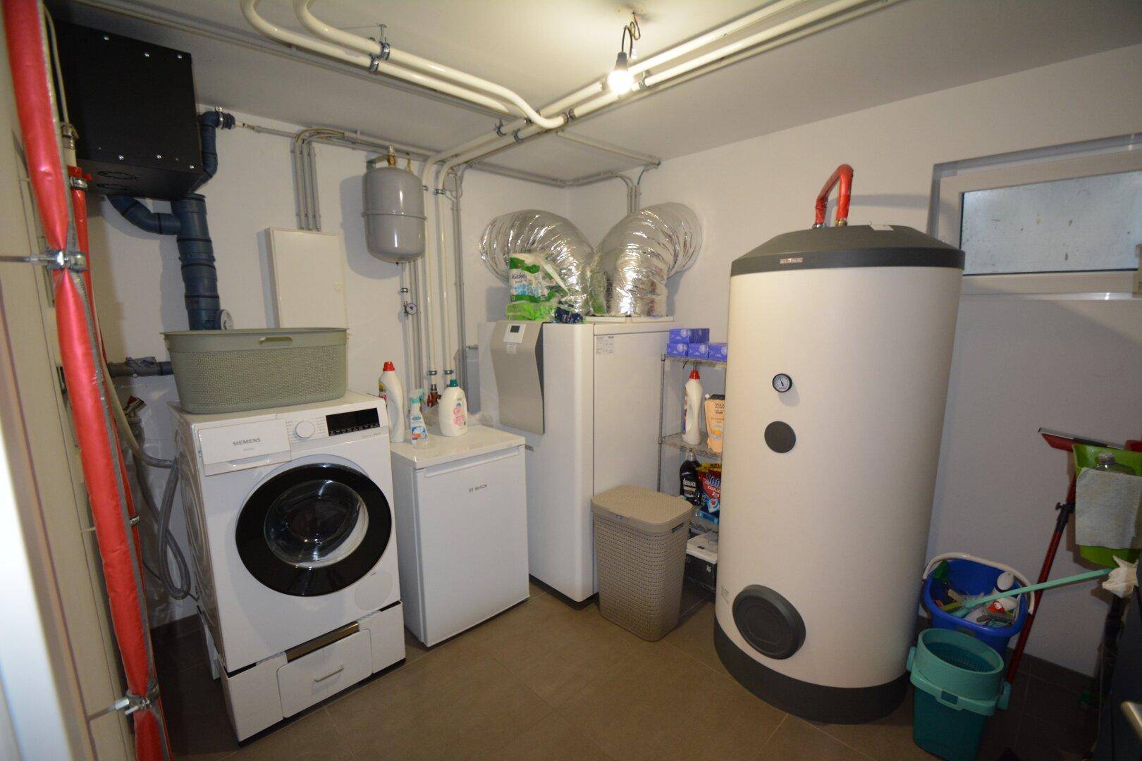 Praktischer Hauswirtschaftsraum im Keller mit Waschmaschine, Trockner und Warmwasserspeicher.