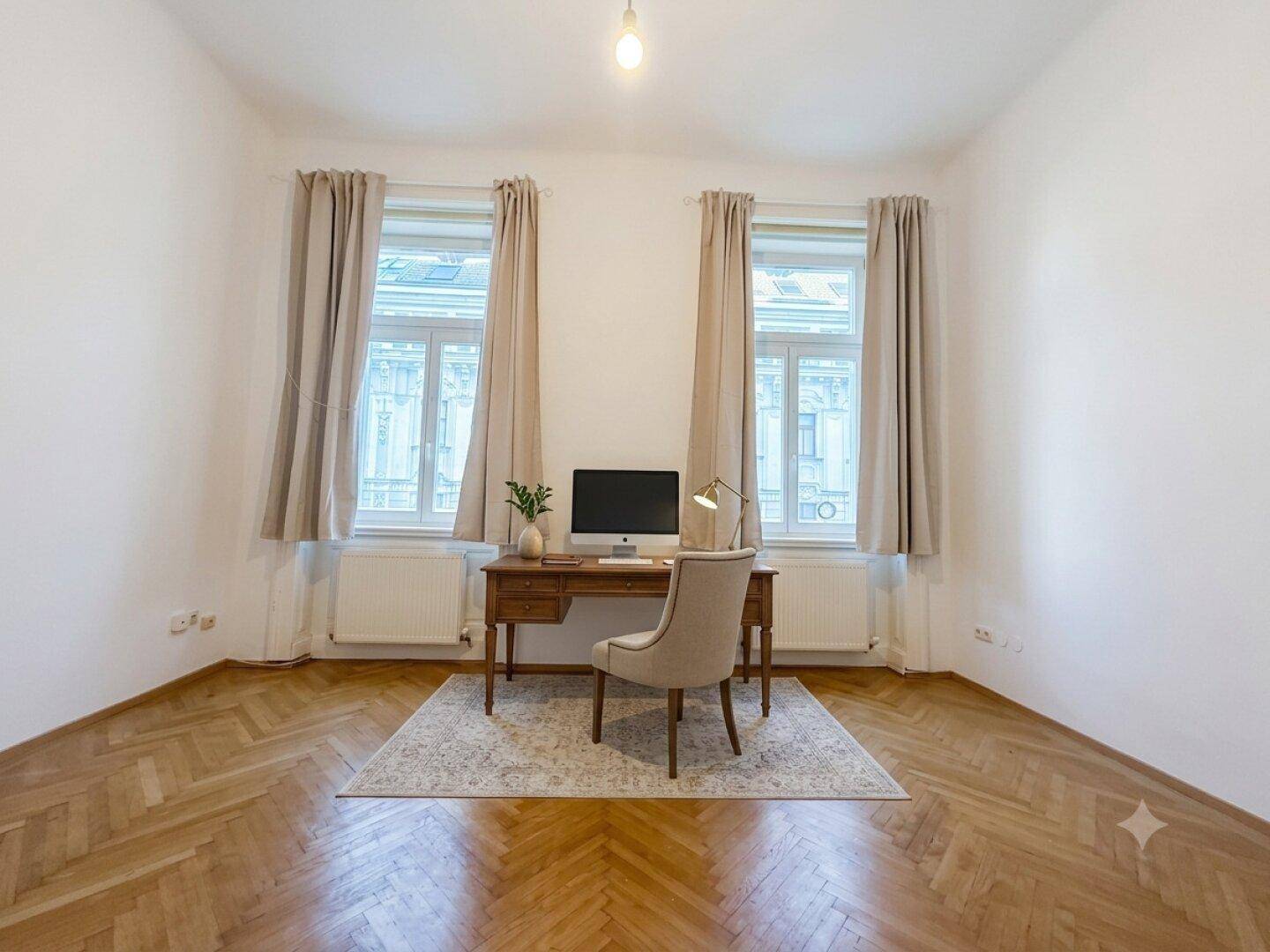 Ruhiges Arbeitszimmer mit Fischgrätparkett, zwei großen Fenstern und einem modernen Schreibtischbereich.