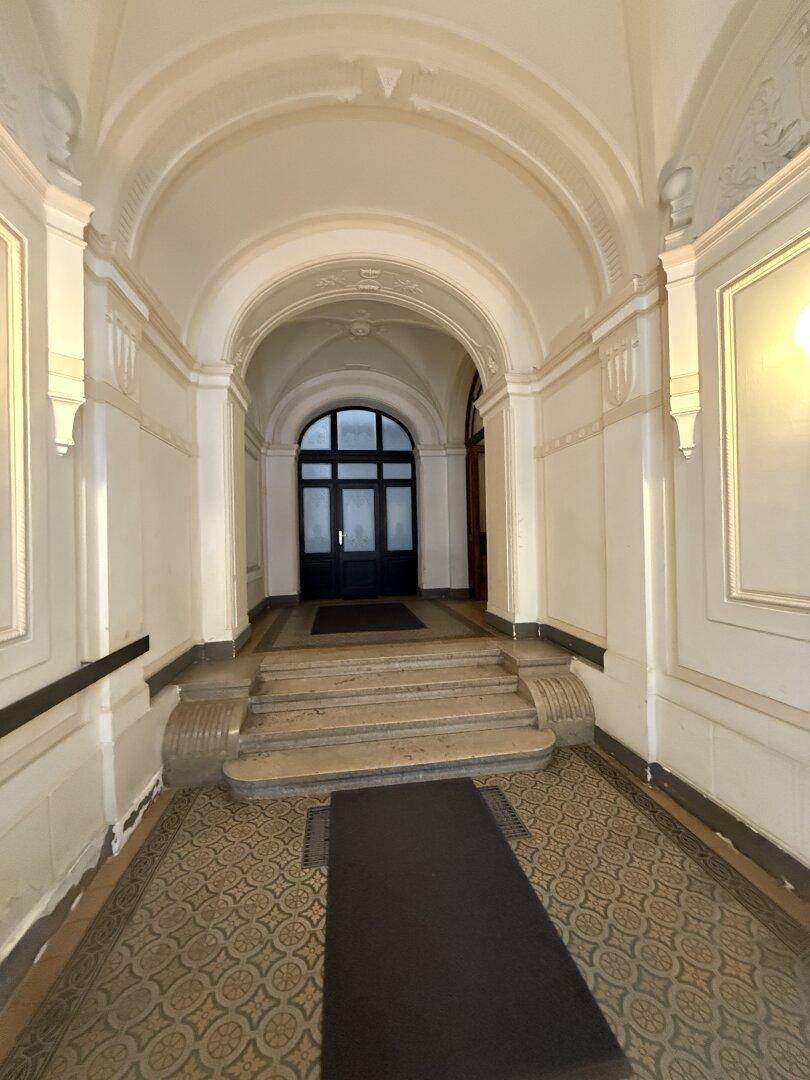 Prunkvoller Eingangsbereich eines Altbaus mit hohen Gewölbedecken und historischen Fliesenböden.