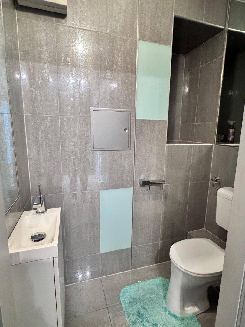 Modernes Gäste-WC mit kleinem Waschbecken und Wand-WC.