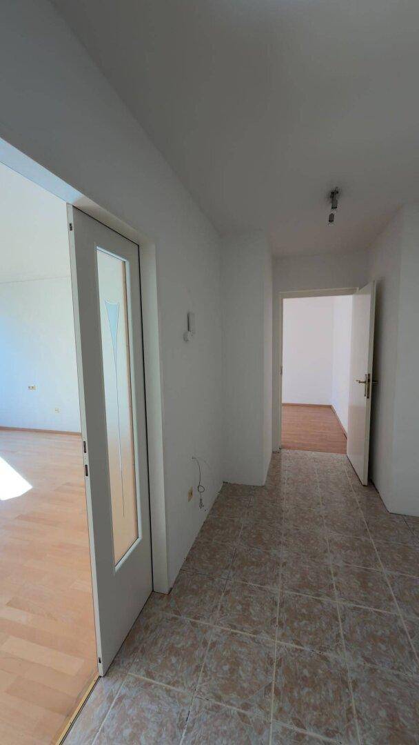 Heller Flur mit Fliesenboden und Zugang zu weiteren Räumen der Wohnung.