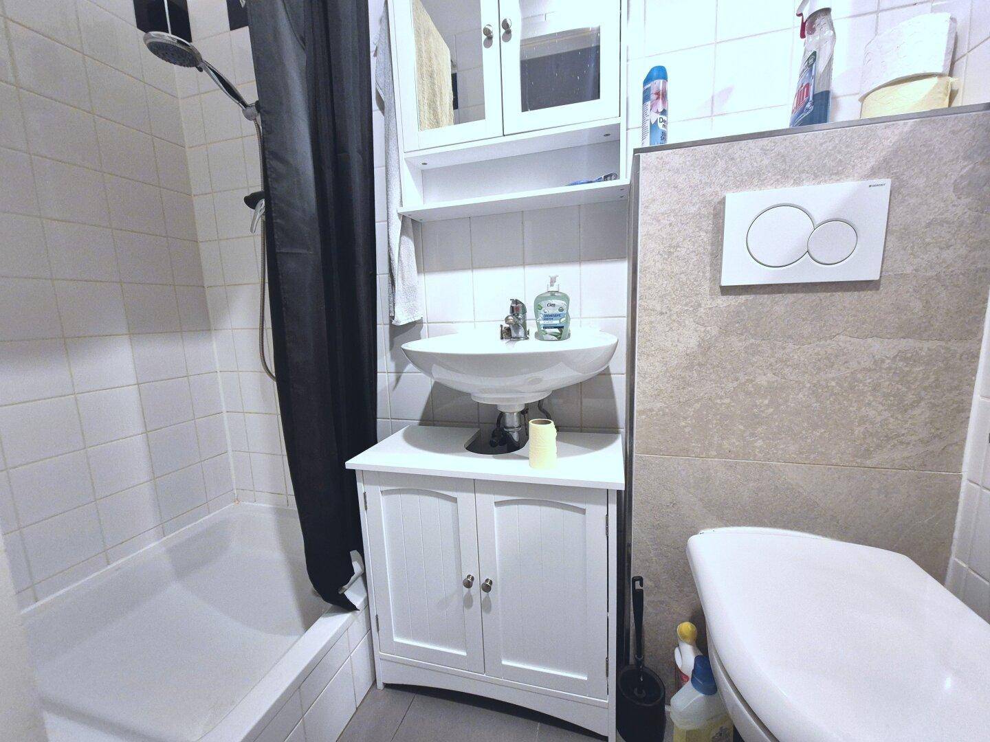 Funktionales Badezimmer mit Badewanne, Duschvorhang, Waschbecken und wandhängendem WC.