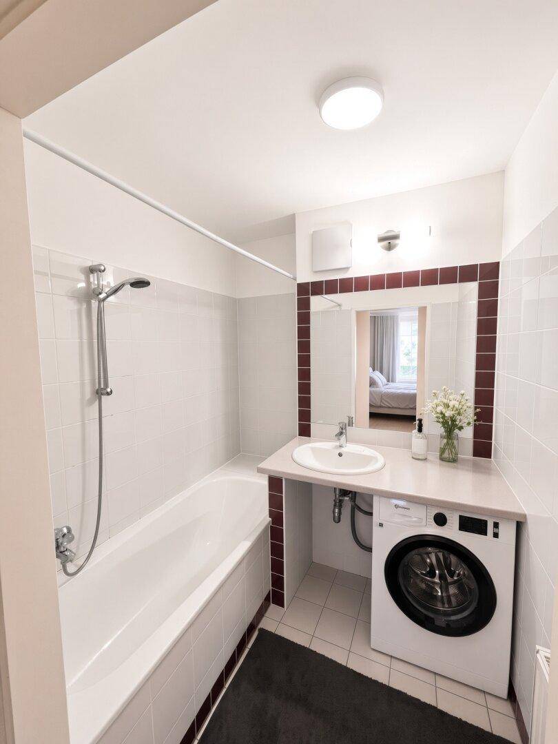 Badezimmer mit Badewanne, Waschbecken und integrierter Waschmaschine.