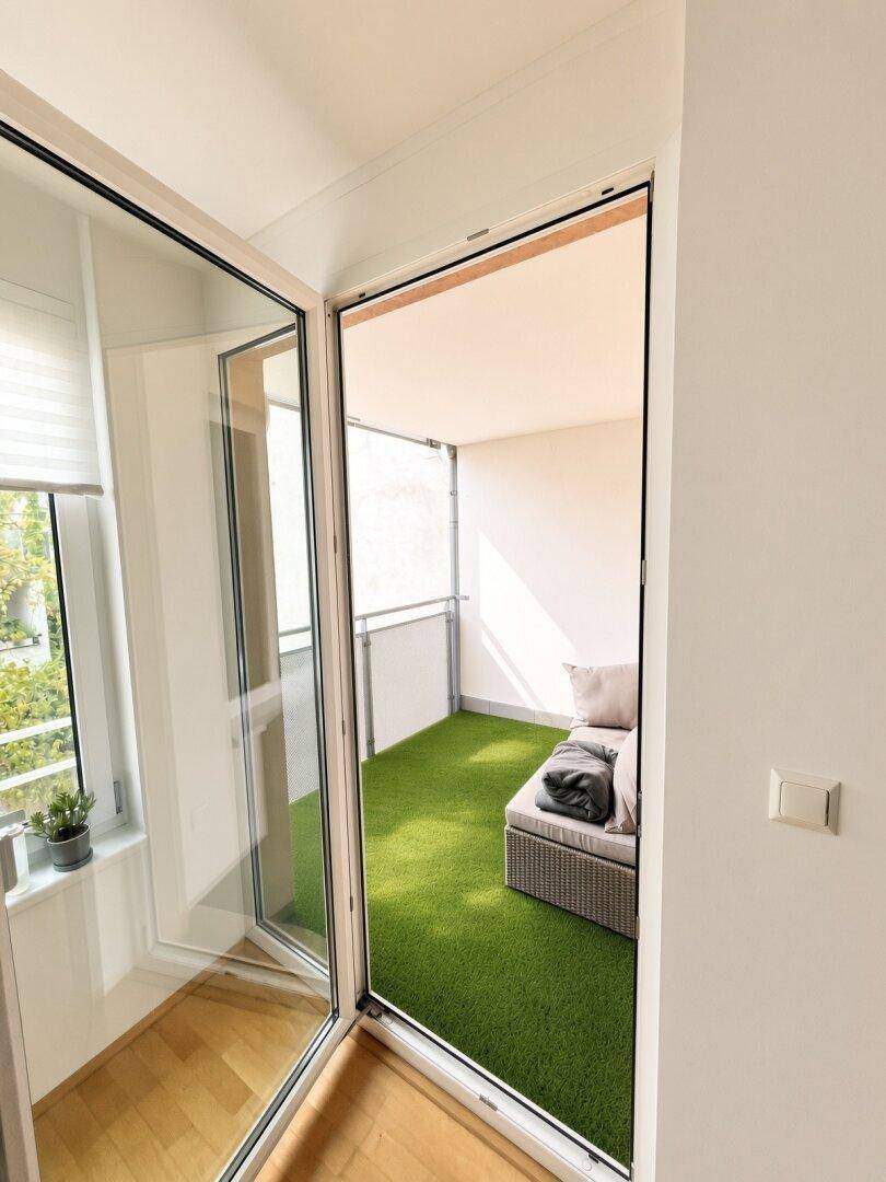 Gemütlicher Balkon mit Kunstrasen und bequemen Outdoor-Möbeln für Entspannung im Freien.