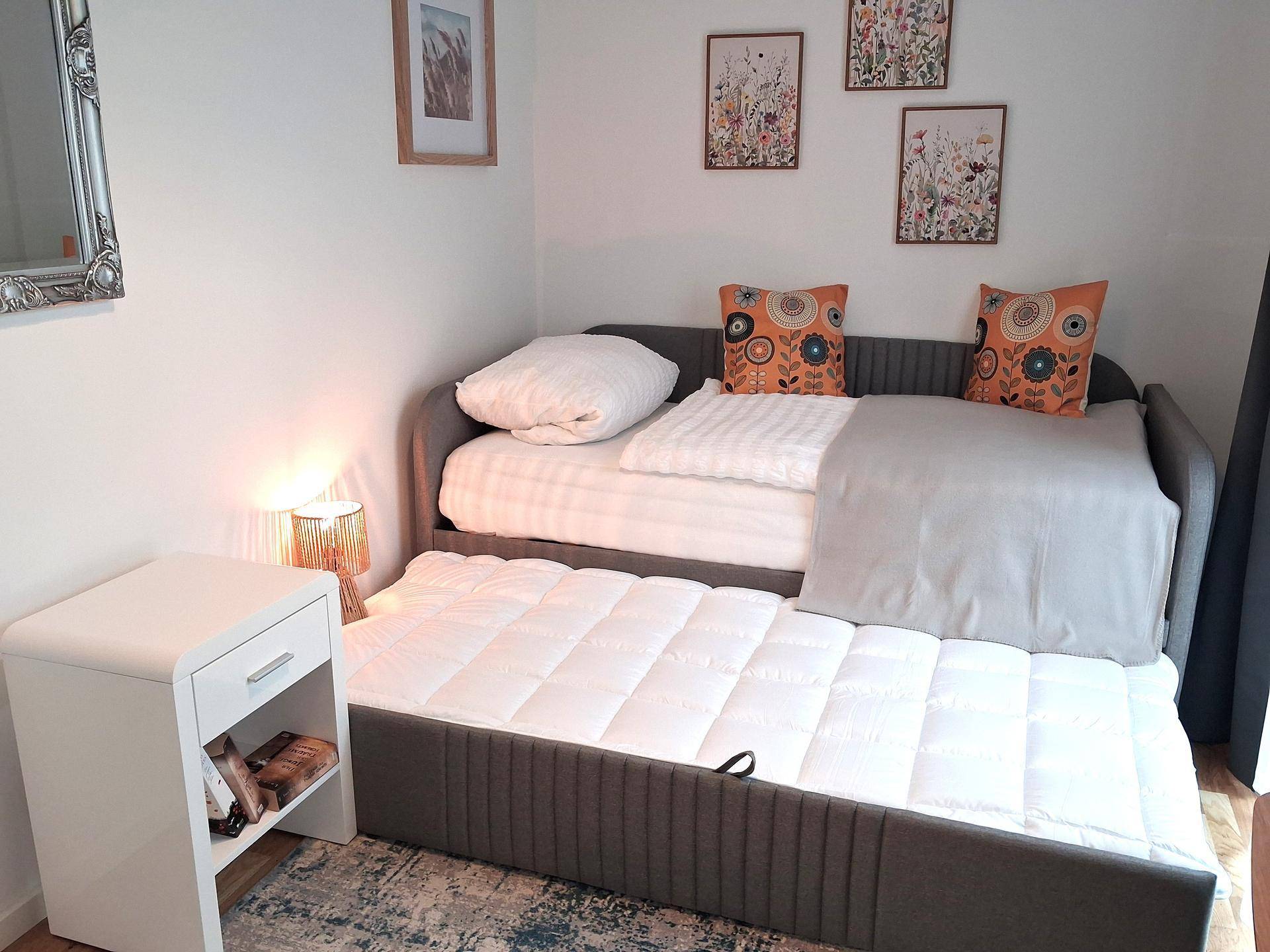 Ausziehbares Tagesbett in einem hellen Zimmer, bietet flexible Schlafmöglichkeiten.