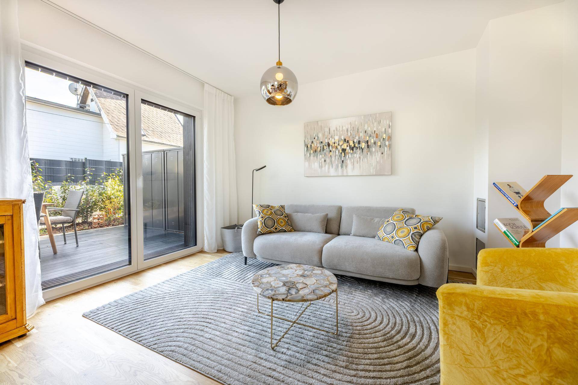 Gemütliches Wohnzimmer mit hellem Sofa, modernem Teppich und direktem Terrassenzugang.