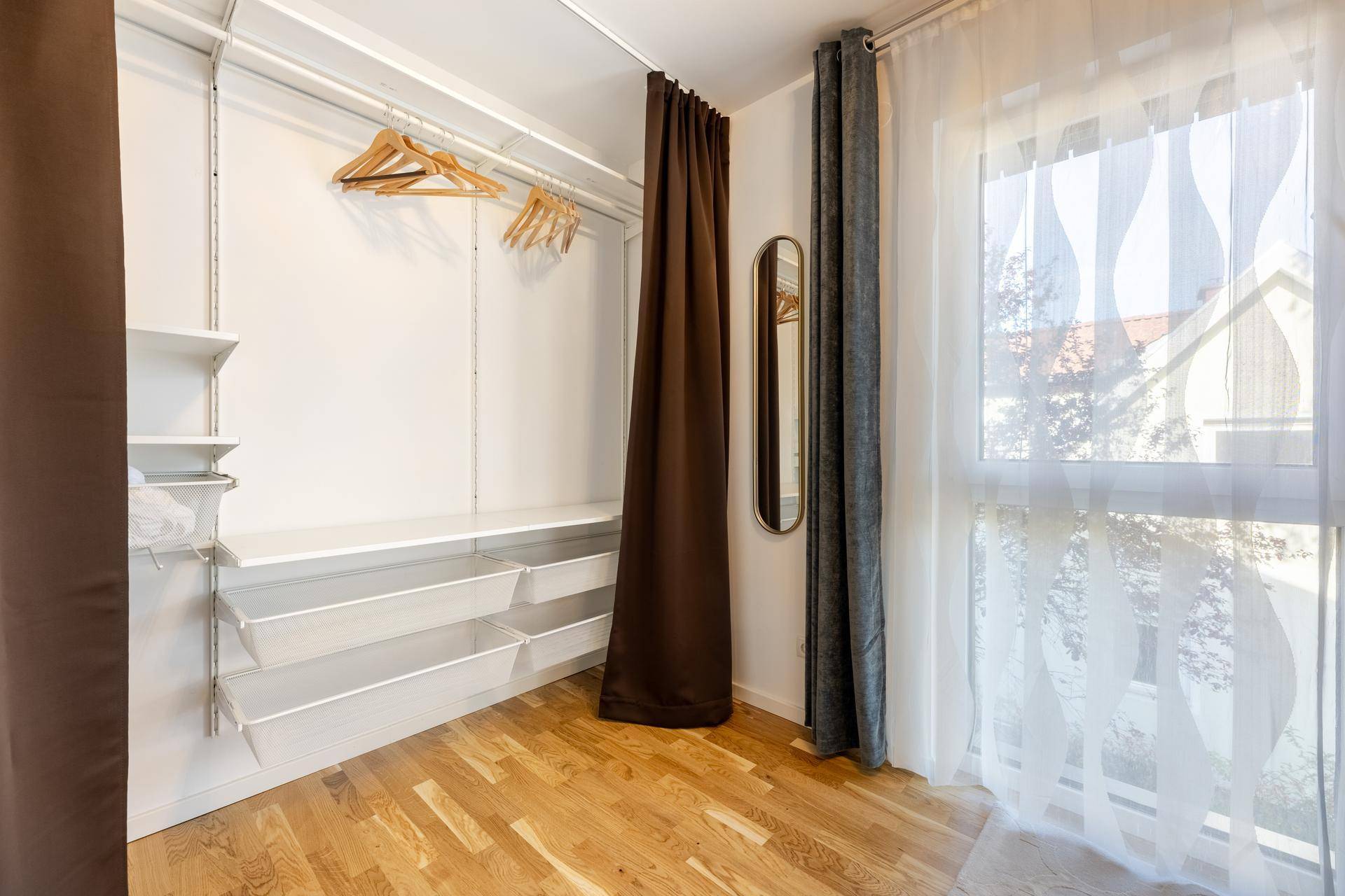 Begehbarer Kleiderschrank mit Regalsystem und Fenster für natürliche Belichtung.