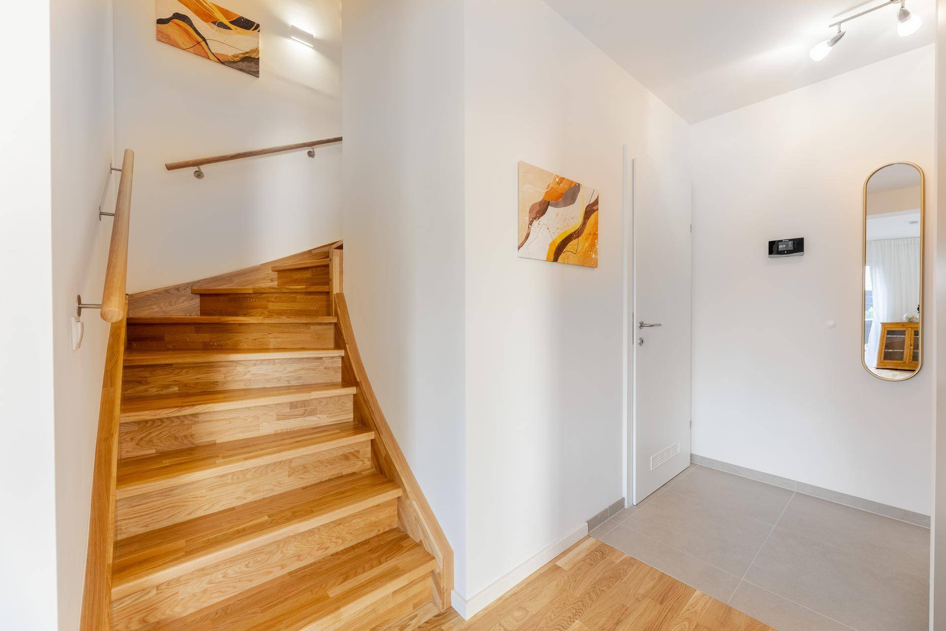 Heller Treppenaufgang mit Holzstufen und Handlauf, führt in die obere Etage.