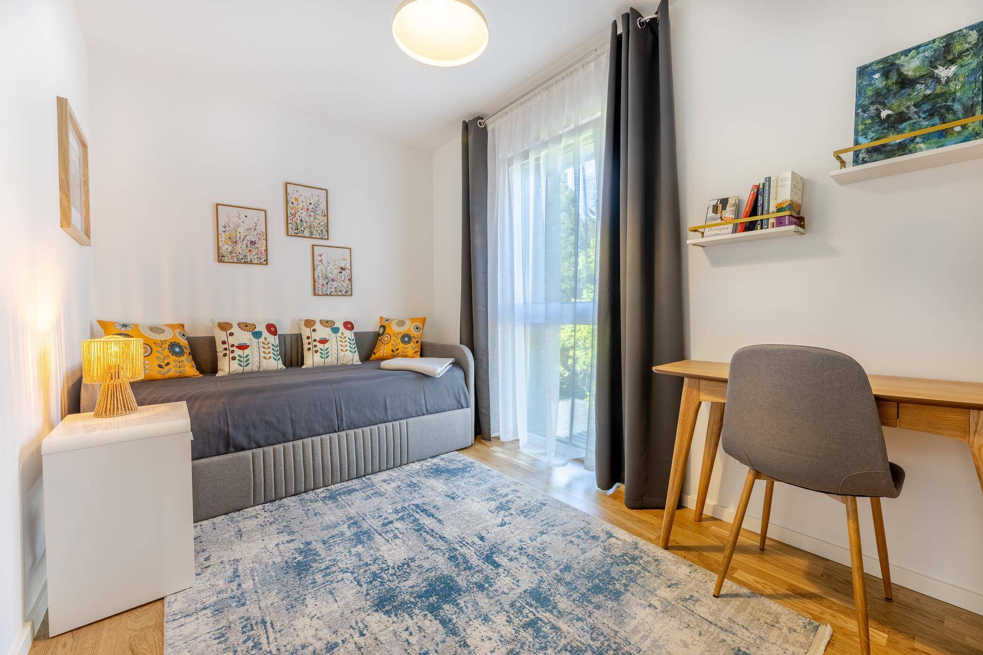 Vielseitiges Zimmer mit Schlafsofa, Schreibtisch und großem Fenster für helles Ambiente.