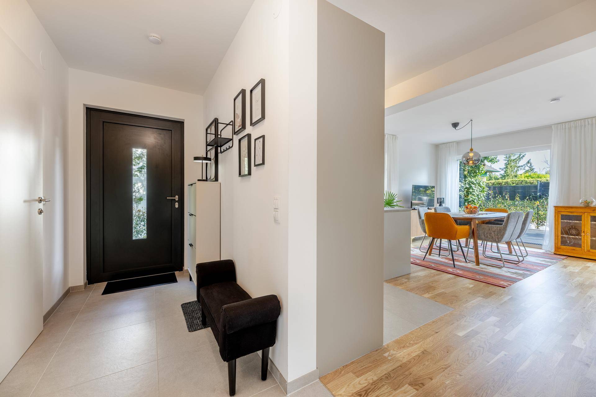 Heller Eingangsbereich mit Fliesenboden, Garderobe und Blick in den offenen Wohnbereich.