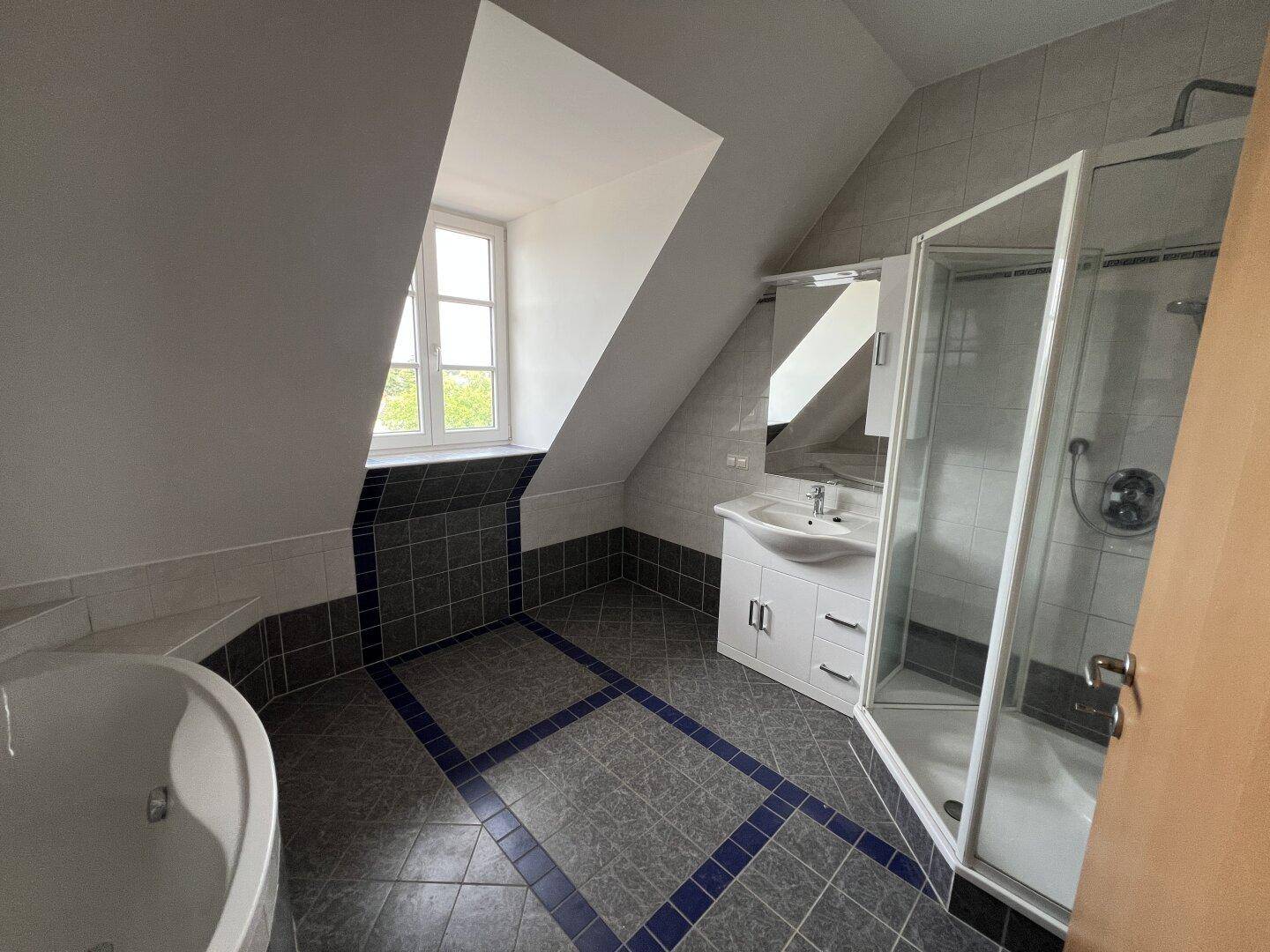 Modernes Badezimmer im Dachgeschoss mit Eckbadewanne, Duschkabine und Fliesenboden.