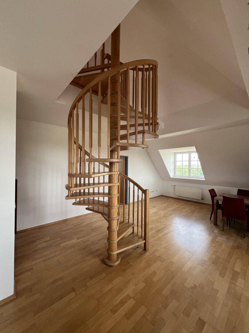 Elegante Holzwendeltreppe als zentrales Element im offenen Wohnbereich.
